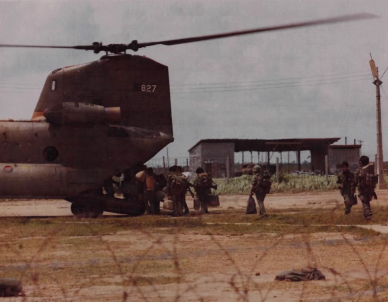 Highland soldiers with packs walking toward a large twin-rotor helicopter
