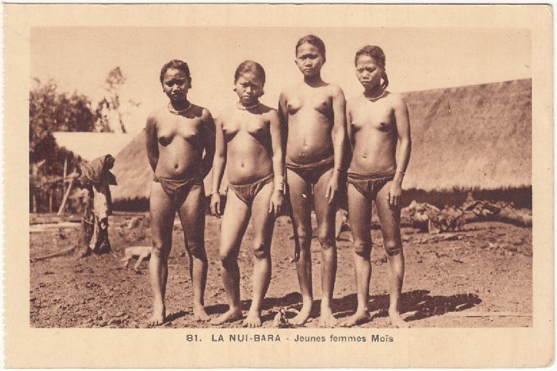 A postcard photograph of a group of highland men standing outside a thatched house