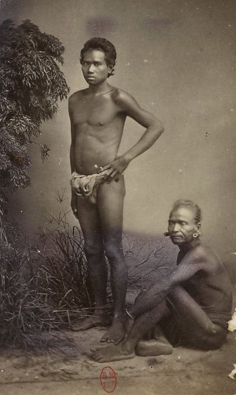 A studio photograph of several Stieng men standing and seated, bare-chested, with spears