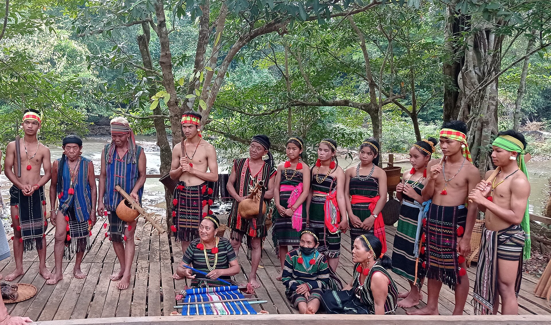 A group of Bunong men and women in ceremonial dress standing on a wooden platform