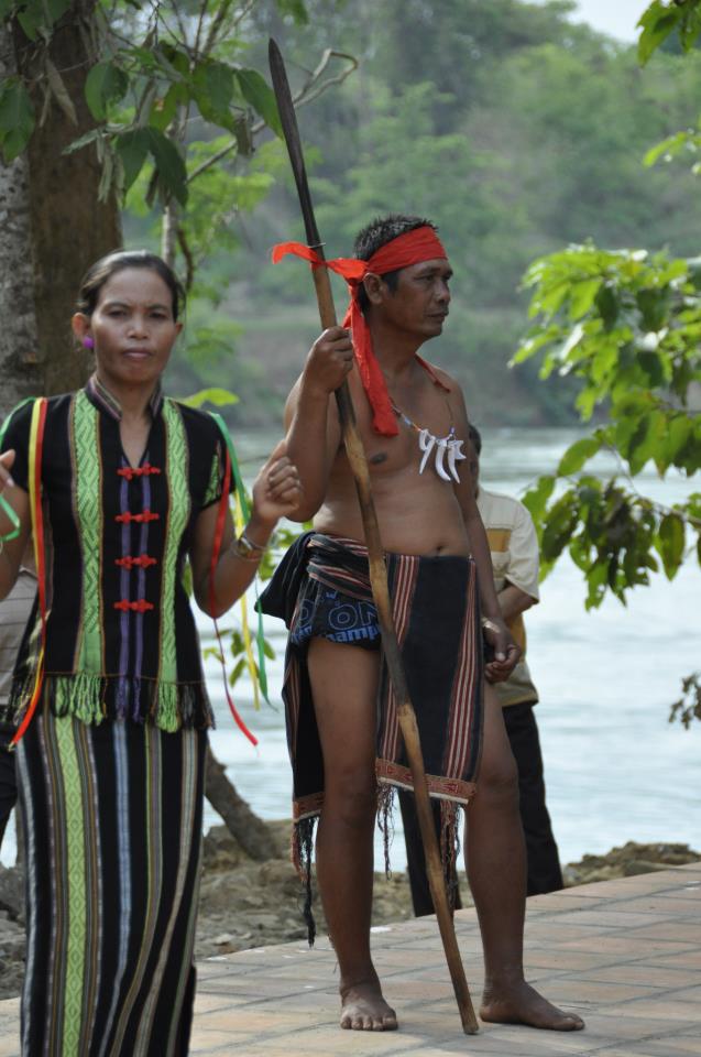 Mnong men in ceremonial dress holding spears at an elephant ceremony